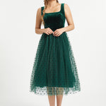 Full-length studio view of emerald green velvet dress with layered polka dot tulle skirt