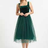 Full-length studio view of emerald green velvet dress with layered polka dot tulle skirt