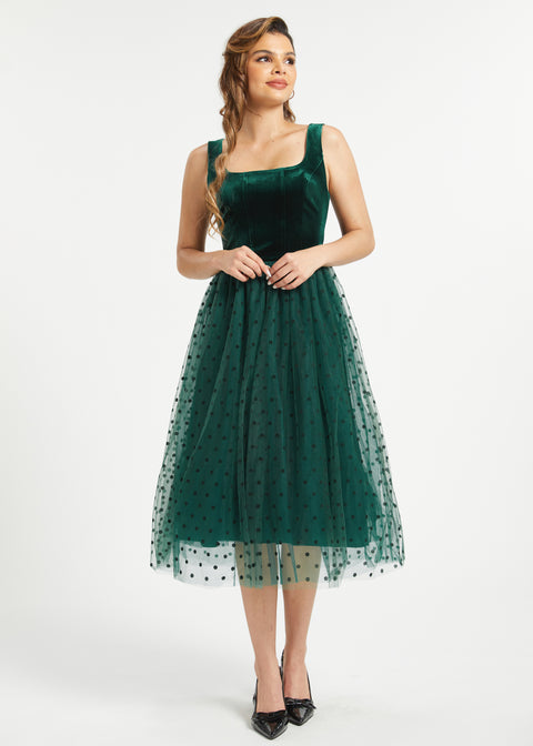 Full-length studio view of emerald green velvet dress with layered polka dot tulle skirt
