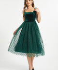 Full front studio view of woman wearing emerald green velvet fit and flare midi dress