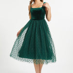 Full front studio view of woman wearing emerald green velvet fit and flare midi dress