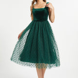 Full front studio view of woman wearing emerald green velvet fit and flare midi dress