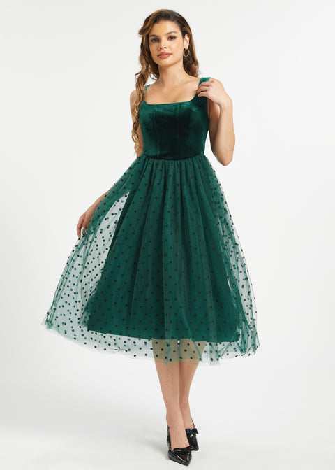 Full front studio view of woman wearing emerald green velvet fit and flare midi dress