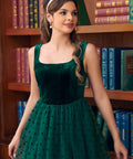 Close-up of woman wearing emerald green velvet dress with flocked polka dot tulle skirt