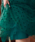 Close-up of layered emerald green flocked polka dot tulle skirt
