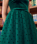 Close-up front view of emerald green velvet square neck bodice and polka dot tulle skirt