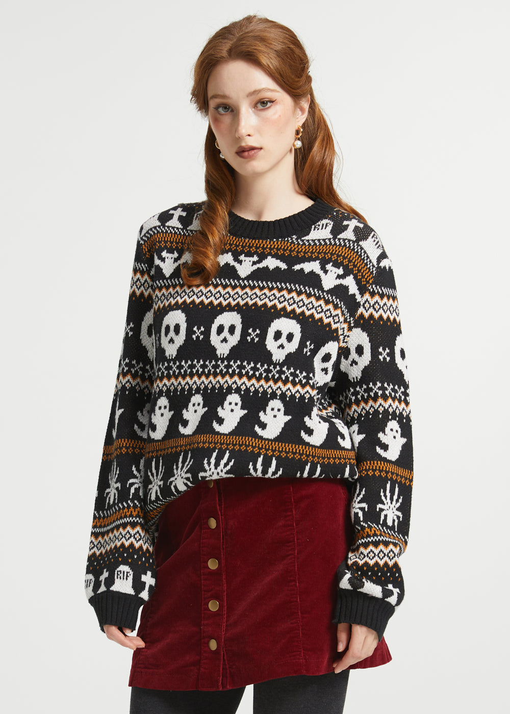 Woman wearing ModCloth Fair Isle Halloween sweater in Creepin' It Cozy featuring ghosts, skulls, bats, spiders, and gravestone knit motifs.
