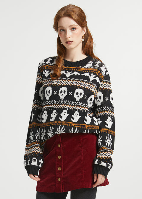 Woman wearing ModCloth Fair Isle Halloween sweater in Creepin' It Cozy featuring ghosts, skulls, bats, spiders, and gravestone knit motifs.