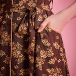 Front slant pocket detail on brown floral dress with removable self-tie belt