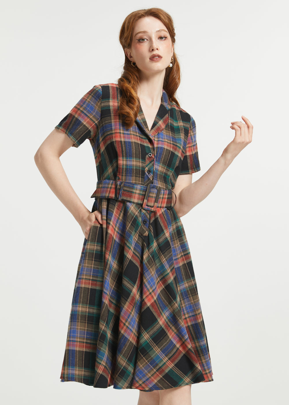 A woman modeling a short-sleeve plaid dress with a collared neckline, button front, and matching tie belt, shown against a plain light gray studio background.