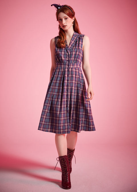 Woman wearing sleeveless plaid dress styled with lace-up ankle boots