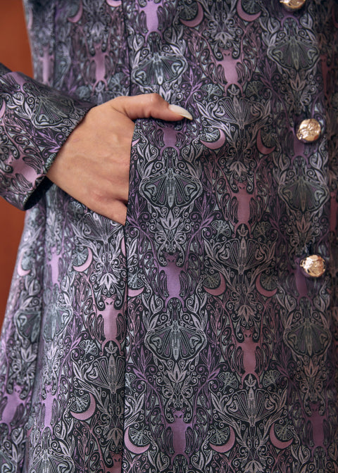Detail of gothic bat and moon brocade pattern on vintage-inspired women's coat