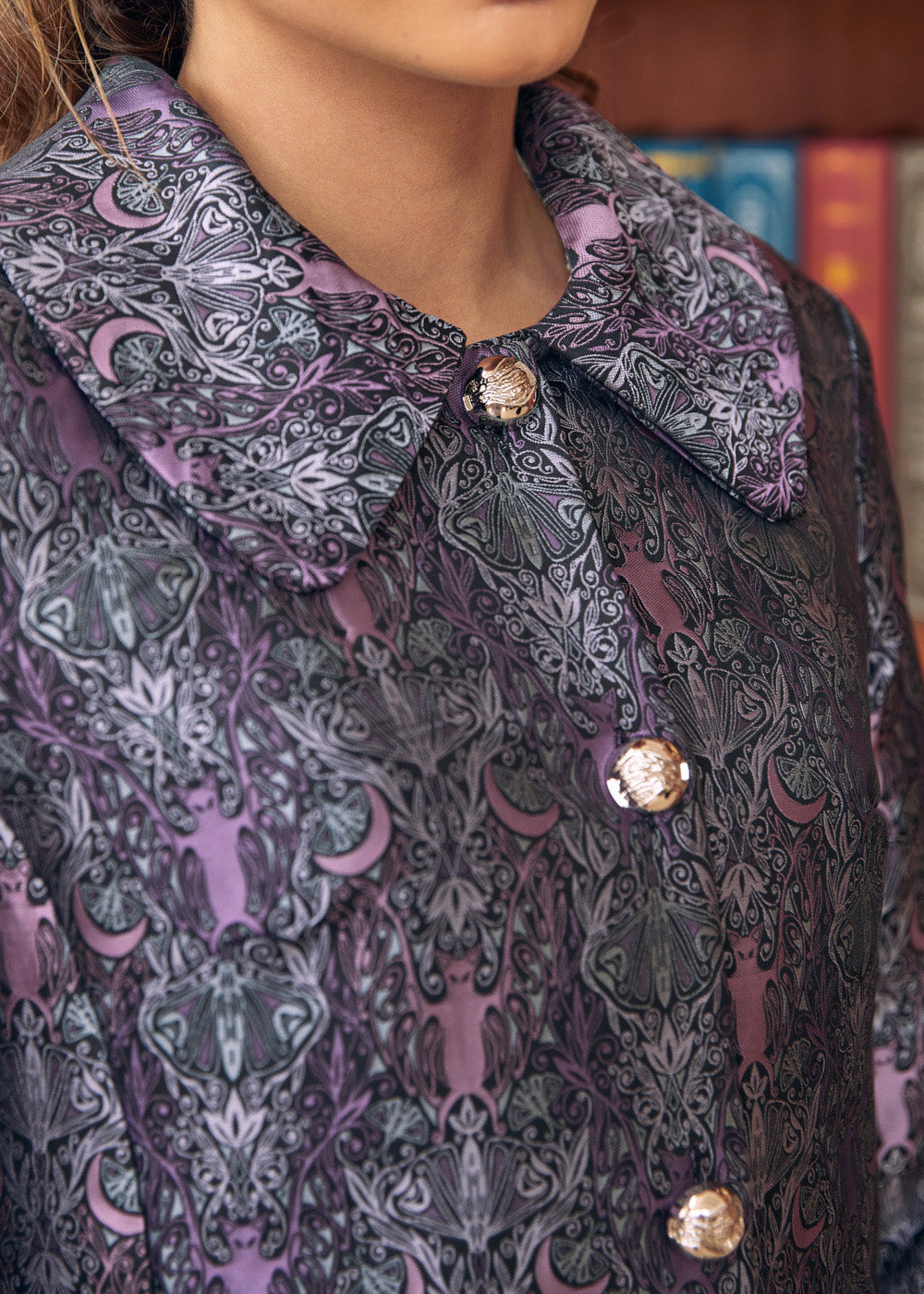 Close-up of women's purple brocade coat with bats crescent moons and botanical motifs