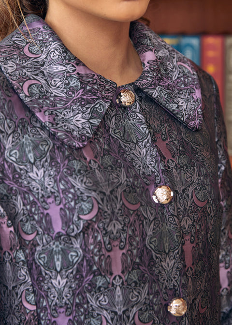 Close-up of women's purple brocade coat with bats crescent moons and botanical motifs