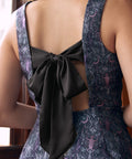 Back view of woman wearing gothic fit and flare dress with open back and oversized black bow