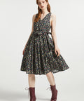 Full-length view of women's cotton faux-wrap fit-and-flare dress with pockets, floral skull print, and removable waist tie styled with burgundy lace-up boots.