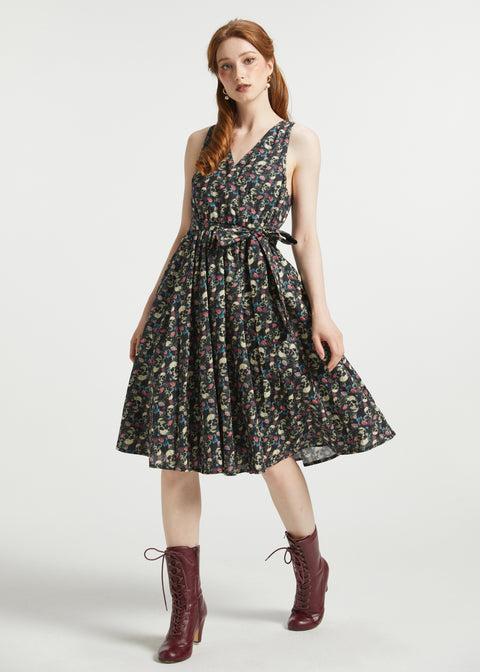 Full-length view of women's cotton faux-wrap fit-and-flare dress with pockets, floral skull print, and removable waist tie styled with burgundy lace-up boots.