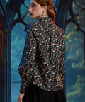 Back view of woman wearing skull floral cotton button-up blouse with curved shirttail hem 
