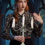 Woman styling gothic skull and floral button-up blouse with candelabra