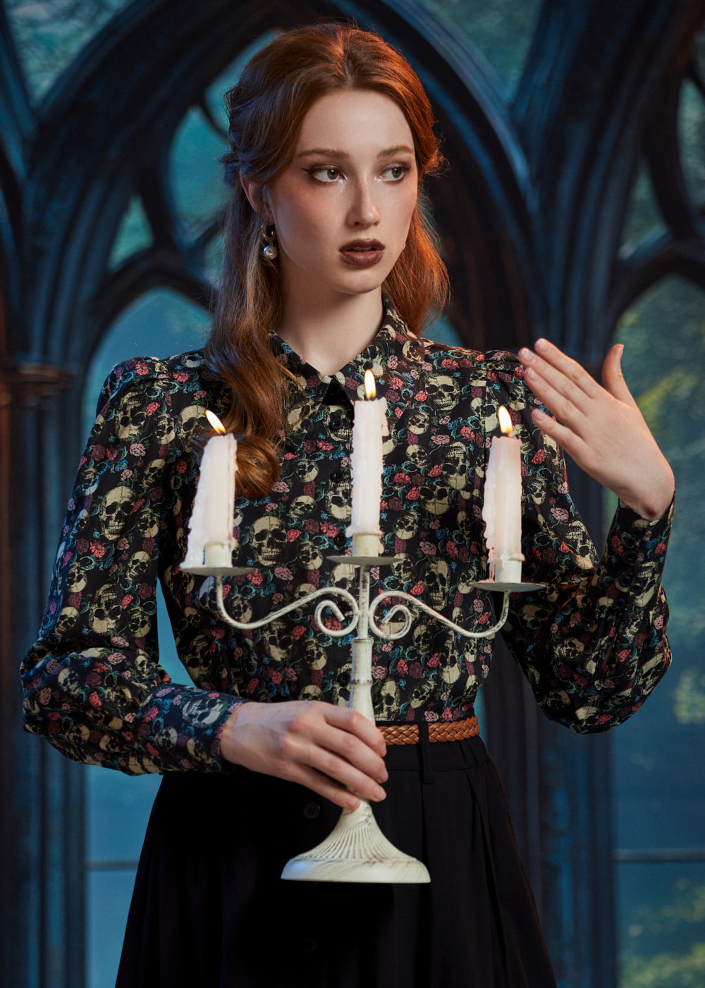 Woman styling gothic skull and floral button-up blouse with candelabra