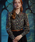 Woman wearing vintage-inspired gothic skull floral blouse tucked into black skirt 