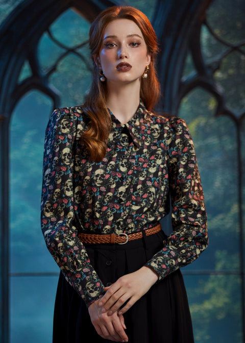 Woman wearing vintage-inspired gothic skull floral blouse tucked into black skirt 