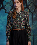 Woman wearing gothic skull floral button-up blouse with pointed collar and puff shoulders