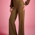 Three-quarter view of woman wearing high waisted houndstooth wide leg pants with decorative gold-tone waist buttons