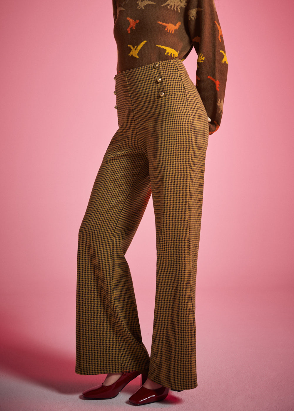Side view of woman wearing golden houndstooth wide leg pants showing the high waist and flowing wide-leg silhouette