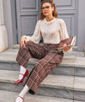 Woman seated wearing brown plaid wide leg culotte pants with side pockets