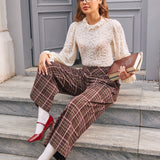 Woman seated wearing brown plaid wide leg culotte pants with side pockets