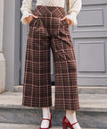 Woman wearing vintage style brown plaid pants with pleated front and pockets