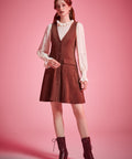 Woman wearing vintage-inspired brown jumper mini dress with blouse and ankle boots
