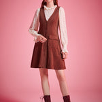 Woman wearing vintage-inspired brown jumper mini dress with blouse and ankle boots