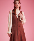 Woman wearing 1970s-inspired A-line jumper dress with deep V-neck and front buttons