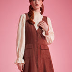 Woman wearing 1970s-inspired A-line jumper dress with deep V-neck and front buttons