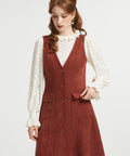 Woman styling rust brown sleeveless jumper dress with cream blouse