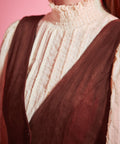 Detail of women's vintage-inspired deep V-neck jumper dress in rust brown