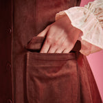 Close-up of women's rust brown button front jumper dress with flap patch pocket