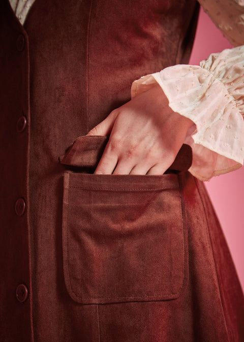 Close-up of women's rust brown button front jumper dress with flap patch pocket