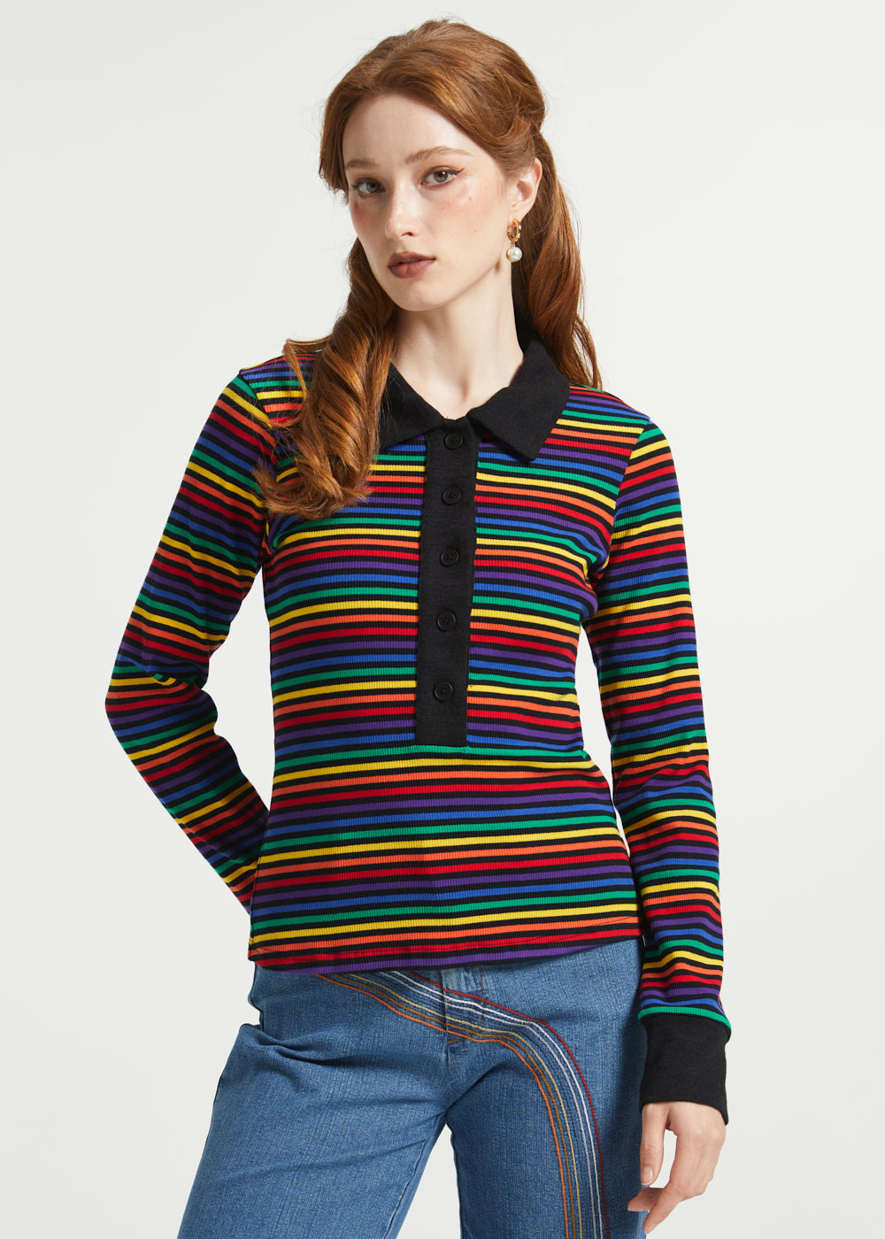 Woman wearing retro rainbow striped cotton polo shirt with long sleeves and contrast black trim