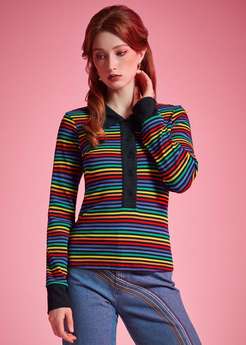 Woman wearing 1970s inspired rainbow striped long sleeve polo shirt with contrast collar