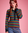 Woman wearing 1970s inspired rainbow striped long sleeve polo shirt with contrast collar