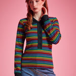 Woman wearing 1970s inspired rainbow striped long sleeve polo shirt with contrast collar