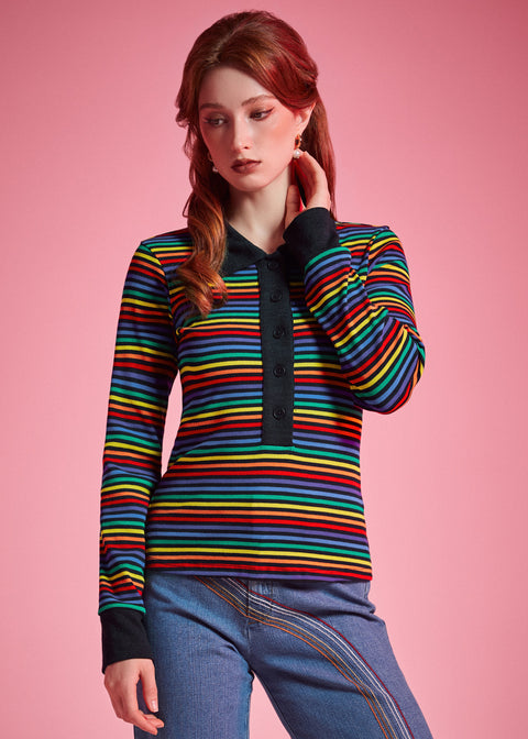 Woman wearing 1970s inspired rainbow striped long sleeve polo shirt with contrast collar