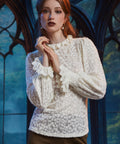 Woman wearing ivory floral lace blouse with ruffled high neckline and long sleeves