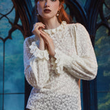 Woman wearing ivory floral lace blouse with ruffled high neckline and long sleeves