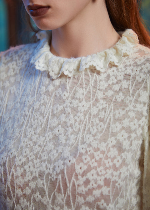 Close-up of ivory floral lace blouse with smocked cuff and layered ruffle trim