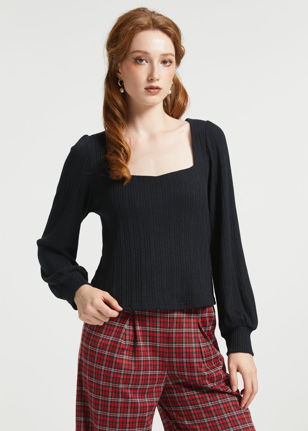 Woman wearing Squarely Smitten black long sleeve top with square neckline and red plaid trousers in studio view