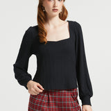 Woman wearing Squarely Smitten black long sleeve top with square neckline and red plaid trousers in studio view